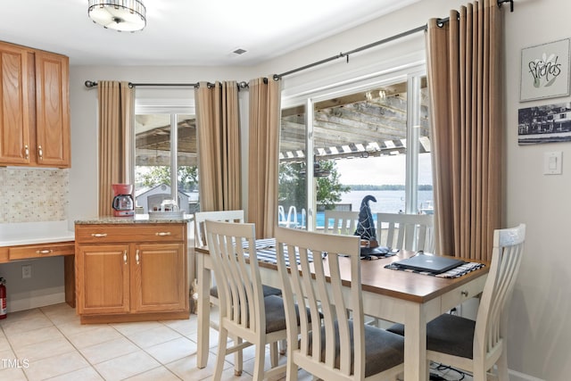 dining space with a water view and light tile patterned floors