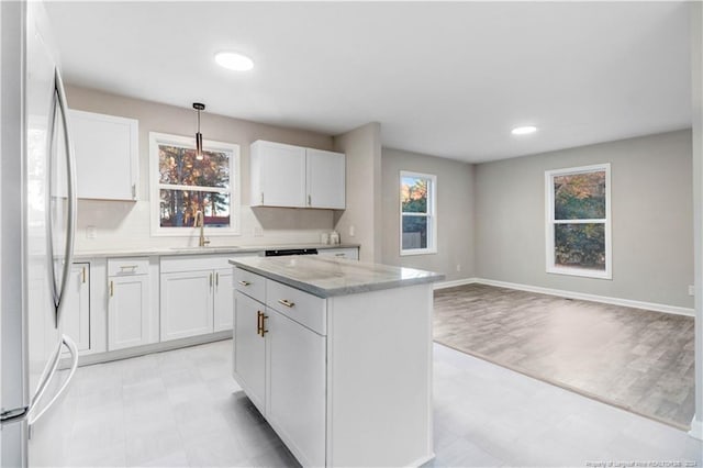 kitchen featuring white cabinetry, stainless steel refrigerator, a wealth of natural light, and a kitchen island