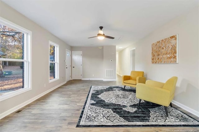 sitting room with ceiling fan and wood-type flooring