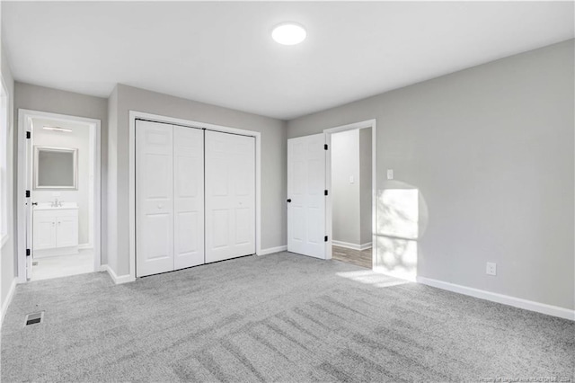 unfurnished bedroom featuring connected bathroom, light carpet, and a closet