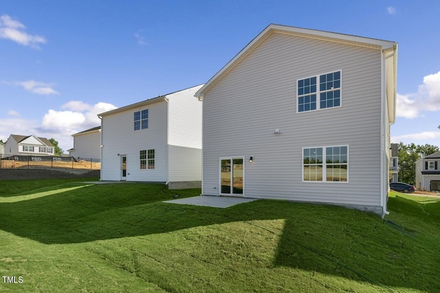 rear view of house featuring a lawn and a patio