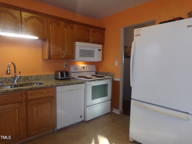 kitchen featuring light stone countertops, white appliances, and sink