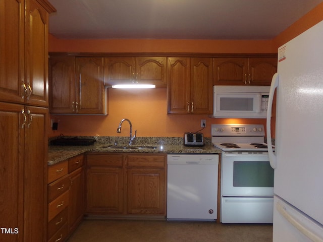 kitchen with white appliances, dark stone countertops, and sink