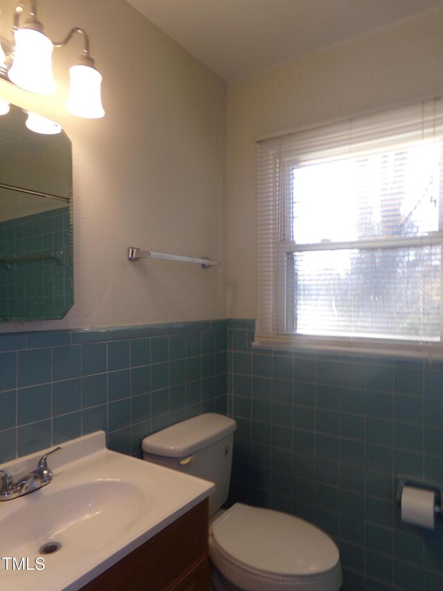 bathroom featuring vanity, tile walls, and toilet