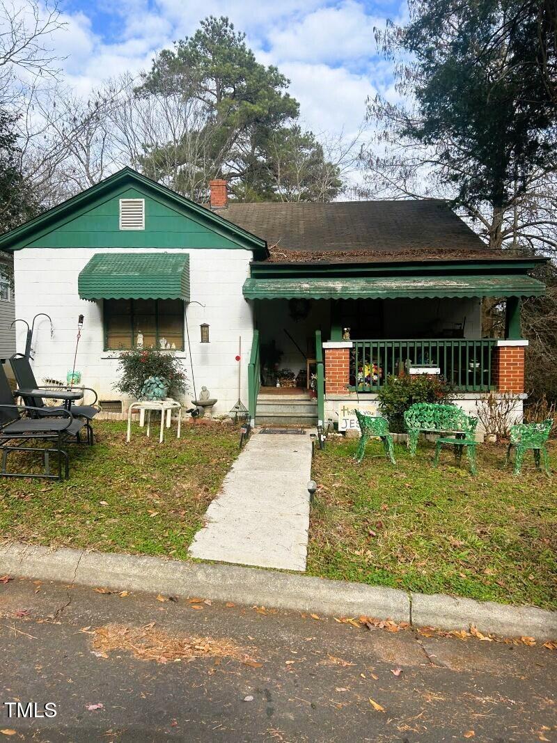 bungalow-style home featuring covered porch and a front lawn