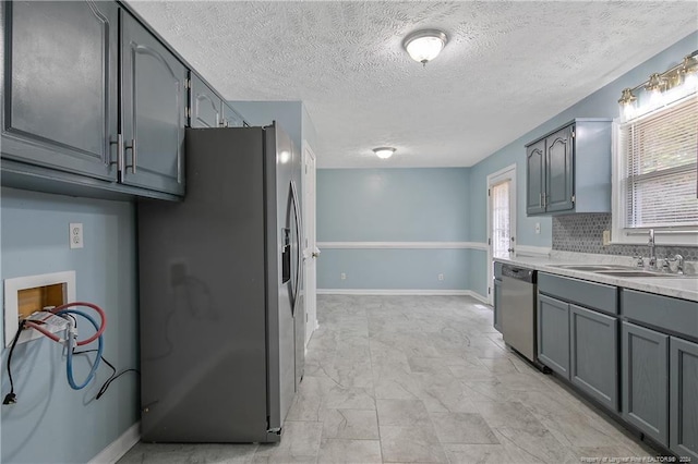 kitchen featuring a textured ceiling, stainless steel appliances, gray cabinets, and sink