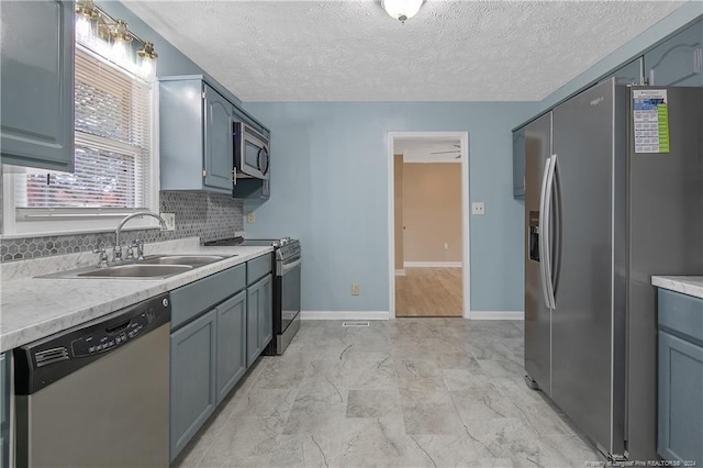 kitchen with decorative backsplash, a textured ceiling, stainless steel appliances, and sink