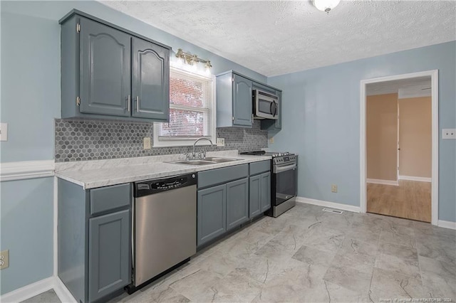 kitchen with gray cabinetry, sink, decorative backsplash, a textured ceiling, and stainless steel appliances