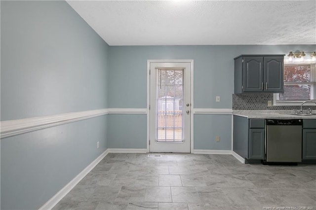 kitchen with gray cabinetry, dishwasher, sink, a textured ceiling, and decorative backsplash