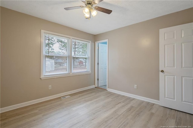 empty room featuring ceiling fan, light hardwood / wood-style floors, and a textured ceiling