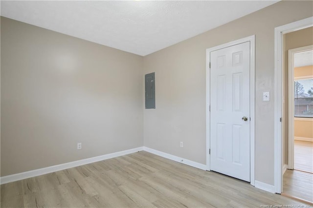 empty room with light wood-type flooring and electric panel