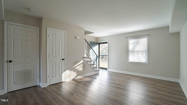 unfurnished room featuring a textured ceiling and dark hardwood / wood-style flooring