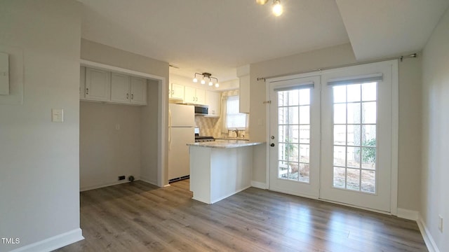 kitchen with white cabinets, light wood-type flooring, white refrigerator, and range