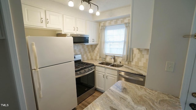 kitchen featuring white cabinets, sink, decorative backsplash, light stone counters, and stainless steel appliances