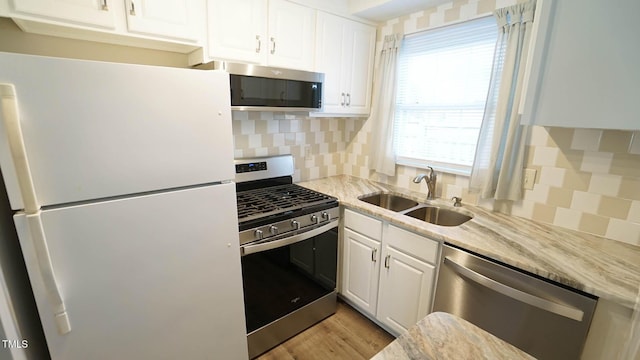 kitchen featuring backsplash, sink, light stone counters, white cabinetry, and stainless steel appliances