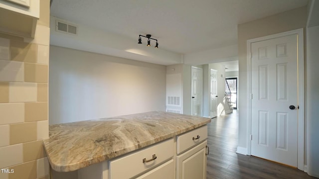 kitchen featuring light stone counters, dark hardwood / wood-style flooring, white cabinets, and track lighting