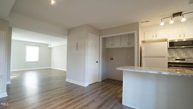 kitchen with backsplash, light stone counters, stainless steel appliances, white cabinets, and hardwood / wood-style floors