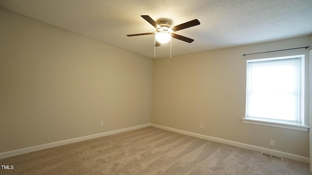 carpeted empty room featuring plenty of natural light, ceiling fan, and a textured ceiling