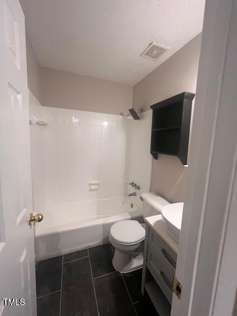 full bathroom featuring tile patterned floors, shower / bath combination, a textured ceiling, toilet, and vanity