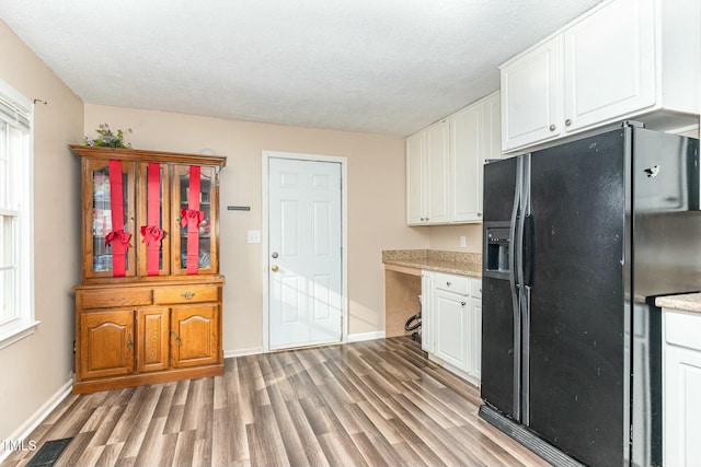 kitchen featuring white cabinetry, black refrigerator with ice dispenser, a textured ceiling, and light wood-type flooring