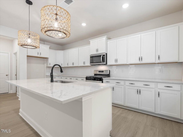 kitchen with pendant lighting, appliances with stainless steel finishes, sink, and white cabinets