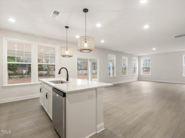 kitchen with sink, hanging light fixtures, stainless steel dishwasher, an island with sink, and white cabinets