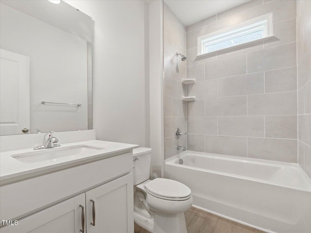 full bathroom featuring tiled shower / bath combo, vanity, wood-type flooring, and toilet