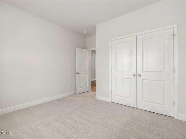 unfurnished bedroom featuring a closet and light carpet