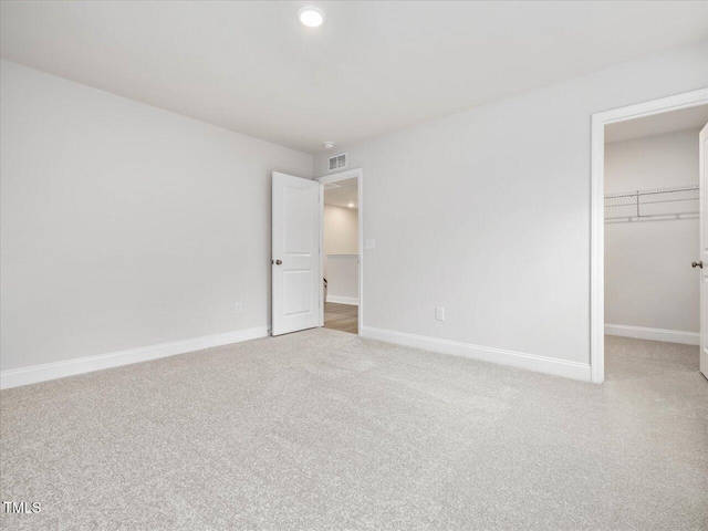 unfurnished bedroom with light colored carpet, a closet, and a walk in closet