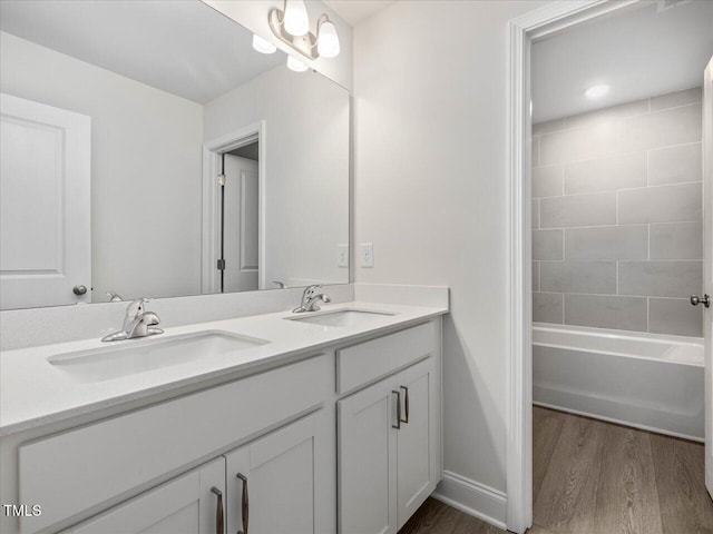 bathroom with tiled shower / bath, wood-type flooring, and vanity