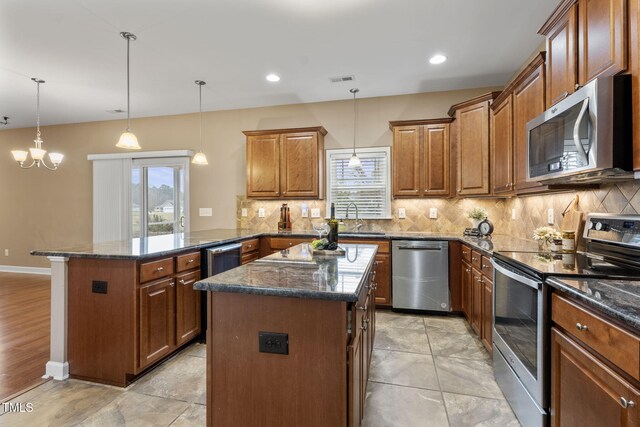 kitchen with a kitchen island, stainless steel appliances, hanging light fixtures, kitchen peninsula, and a chandelier