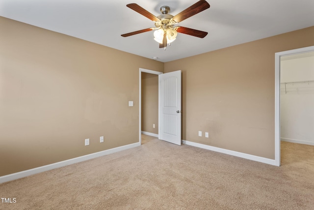 unfurnished bedroom with a spacious closet, ceiling fan, a closet, and light colored carpet