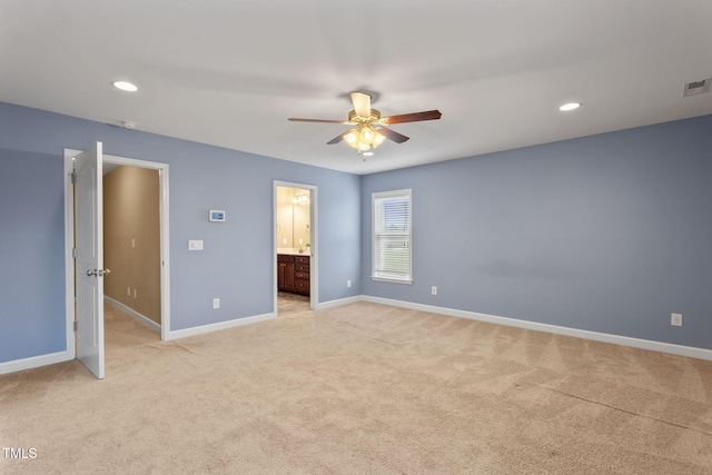 unfurnished bedroom featuring ceiling fan, light colored carpet, and ensuite bathroom