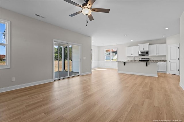 unfurnished living room featuring ceiling fan, light hardwood / wood-style floors, and sink