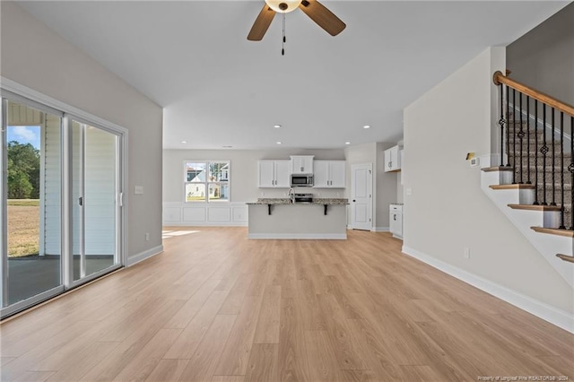 unfurnished living room featuring ceiling fan and light hardwood / wood-style flooring