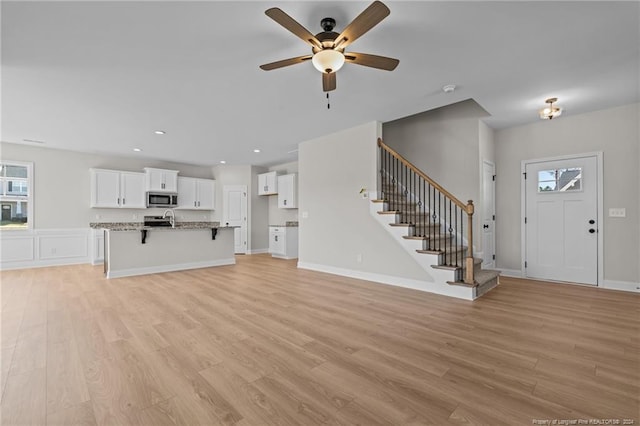 unfurnished living room featuring ceiling fan and light wood-type flooring