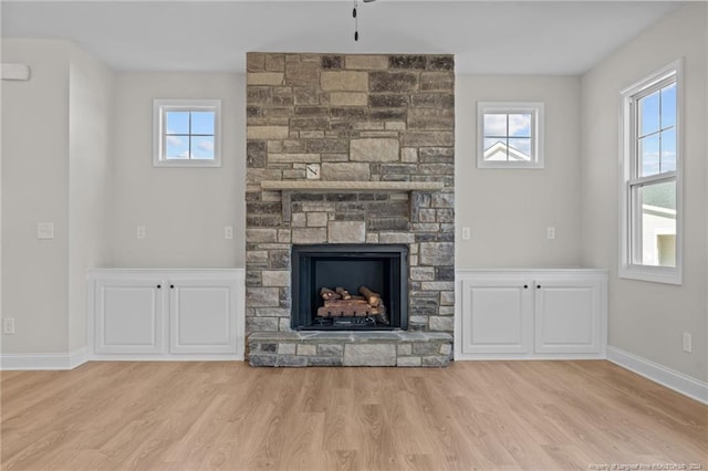 unfurnished living room featuring light wood-type flooring and a stone fireplace