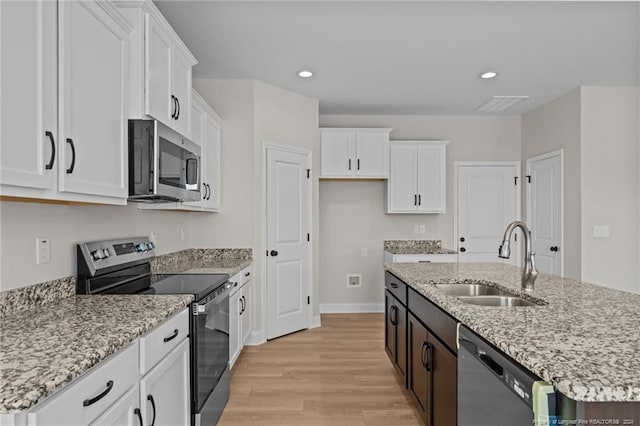 kitchen with sink, appliances with stainless steel finishes, an island with sink, white cabinets, and light wood-type flooring