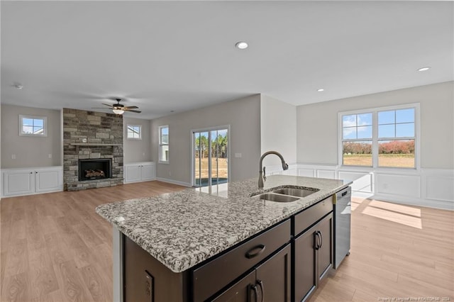 kitchen with a wealth of natural light, sink, stainless steel dishwasher, and light hardwood / wood-style flooring