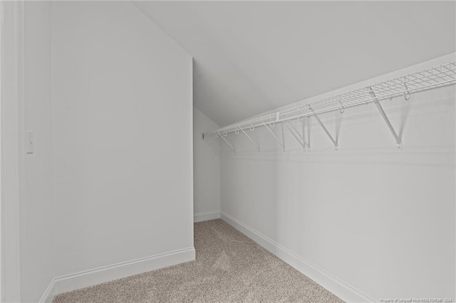 walk in closet with carpet floors and vaulted ceiling