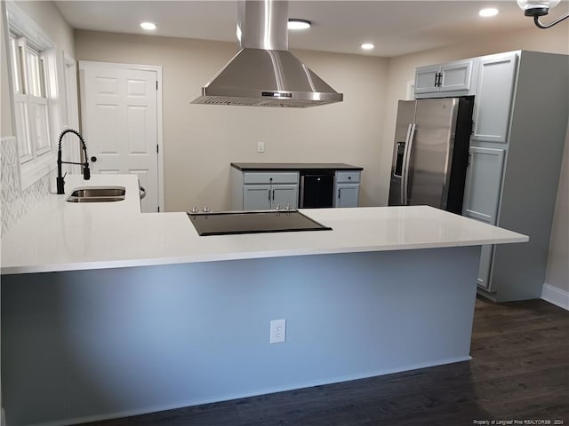 kitchen with kitchen peninsula, stainless steel refrigerator with ice dispenser, sink, wall chimney range hood, and dark hardwood / wood-style floors