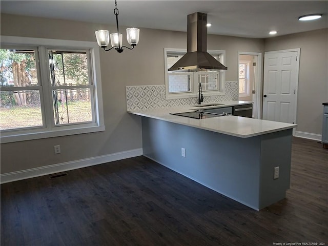 kitchen featuring kitchen peninsula, tasteful backsplash, island range hood, dark wood-type flooring, and pendant lighting