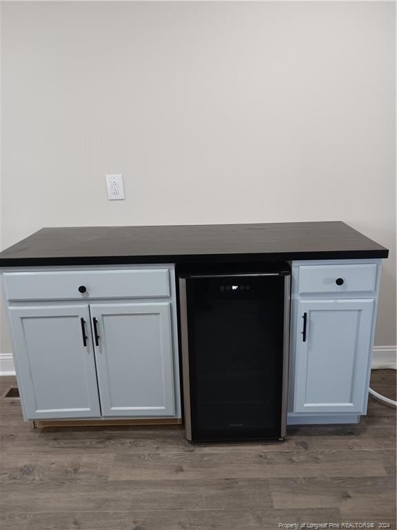 interior details with hardwood / wood-style flooring, wine cooler, and bar area