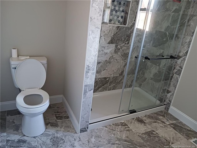 bathroom featuring a shower with shower door and toilet