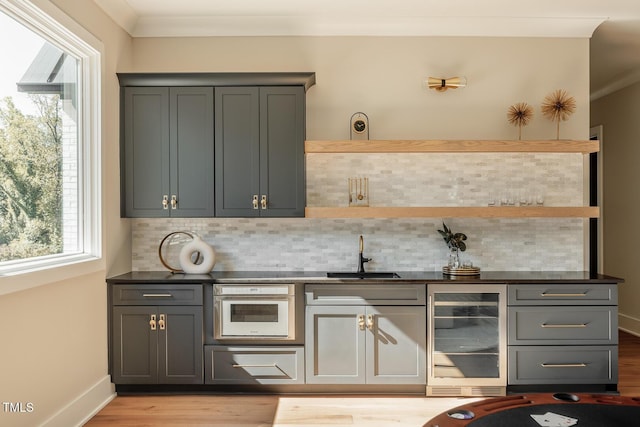 bar featuring gray cabinetry, oven, sink, and beverage cooler