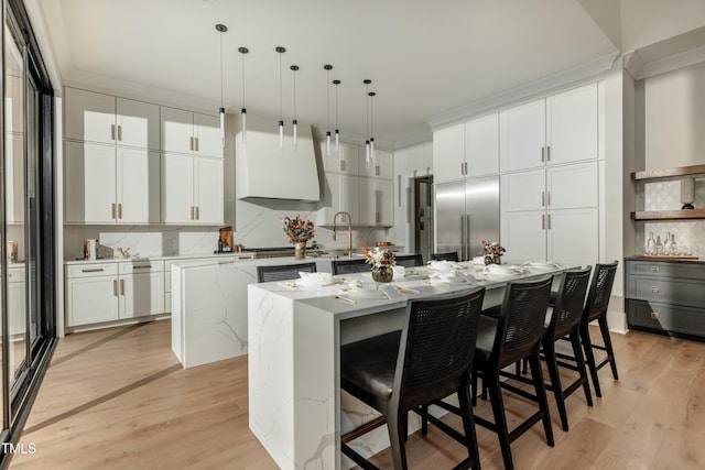 kitchen featuring a kitchen breakfast bar, a center island with sink, pendant lighting, and light hardwood / wood-style flooring