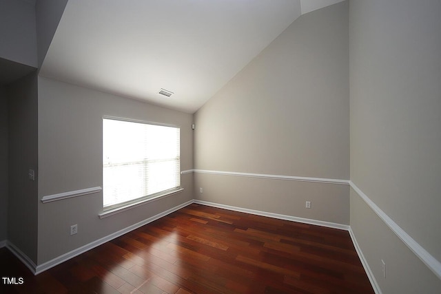 empty room featuring vaulted ceiling and dark wood-type flooring