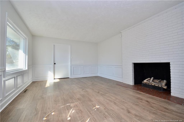 unfurnished living room with a fireplace, wood-type flooring, and a textured ceiling