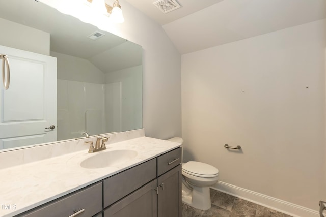 bathroom with a shower, vanity, vaulted ceiling, and toilet