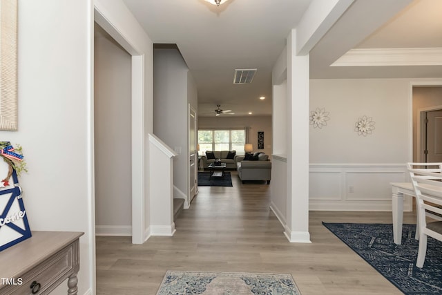 corridor with light hardwood / wood-style floors and crown molding